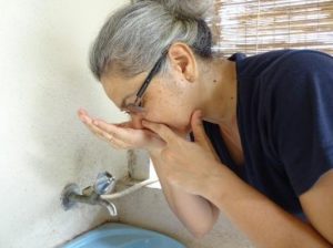 Kvinne åpner tett nese med saltvann fra hånd